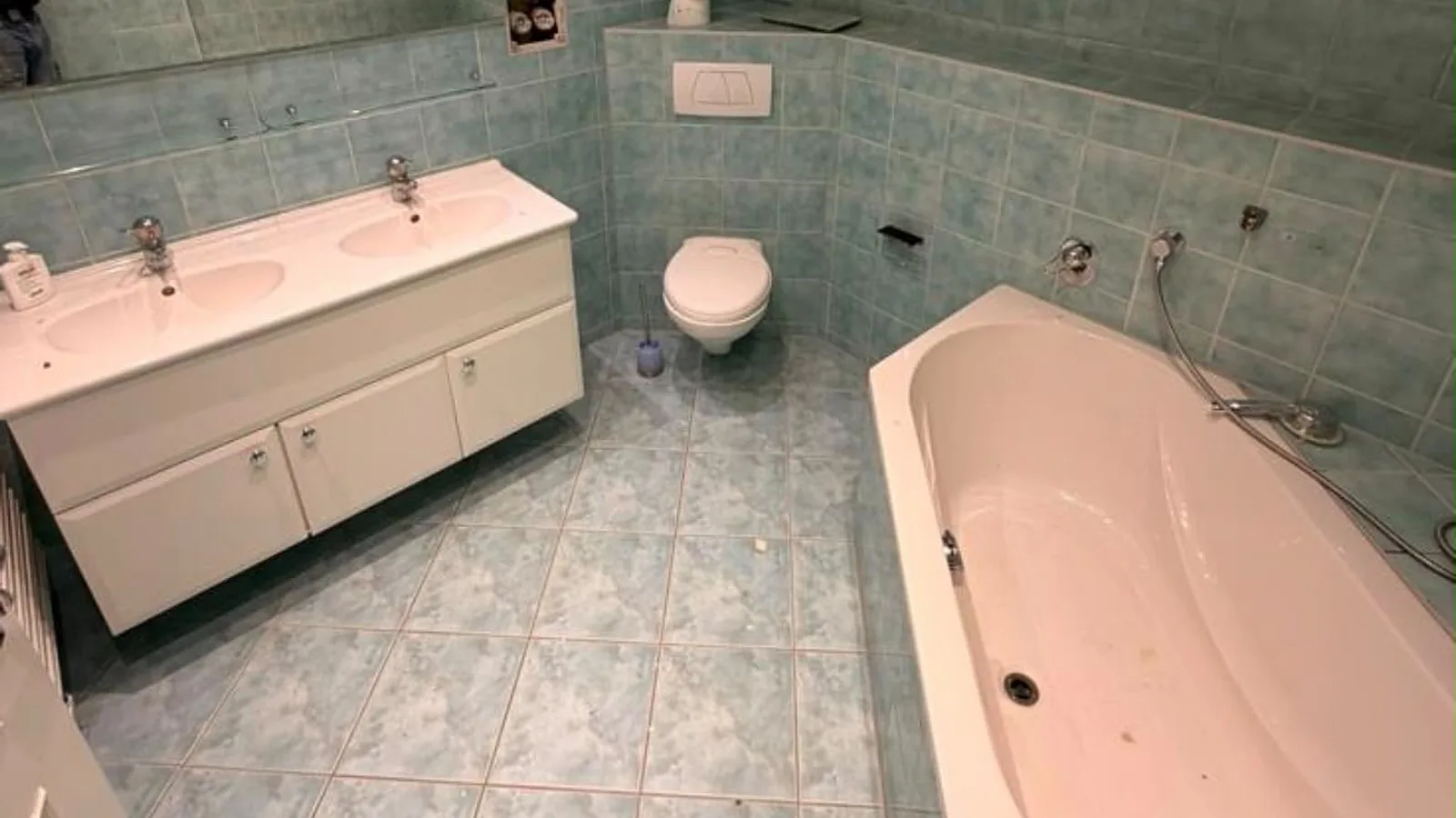 Altes Bad vor dem Umbau mit türkisfarbenen Fliesen, Doppelwaschtisch und Eckbadewanne